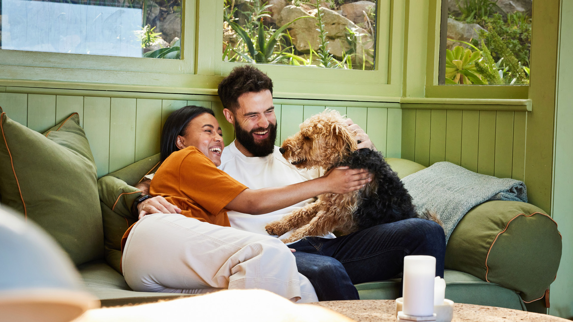 Couple laying on a sofa with their dog laughing